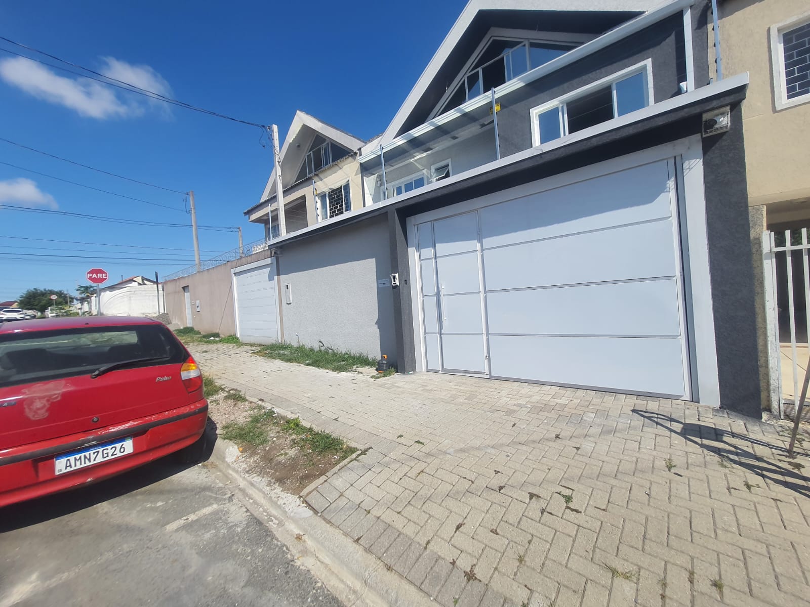 Portão basculante cinza em fachada de tijolo aparente